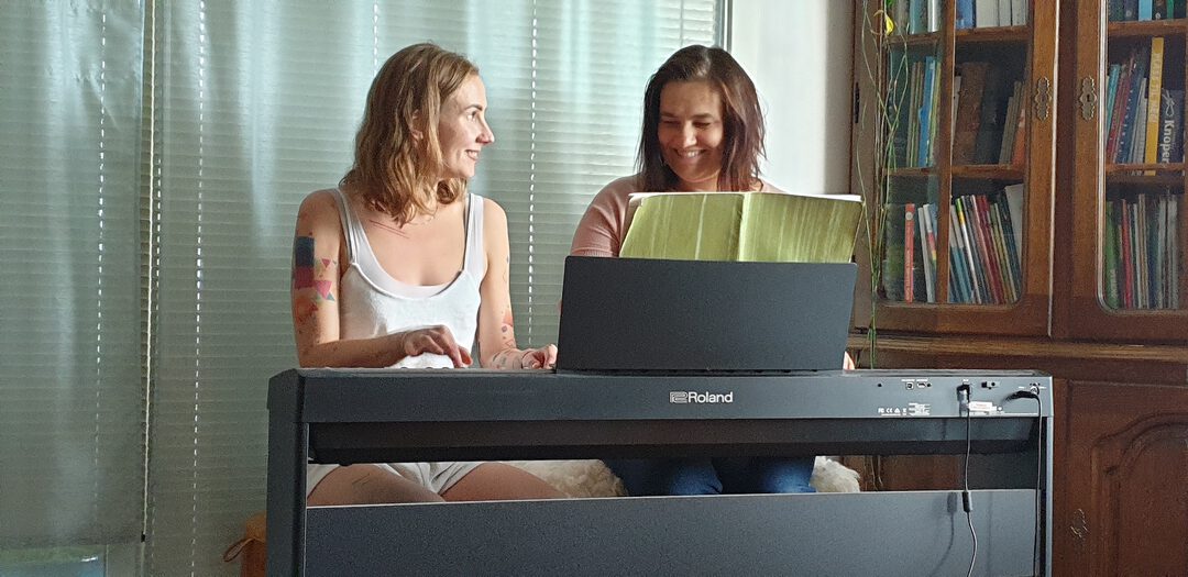 Marta med en voksen kvinne bak et piano