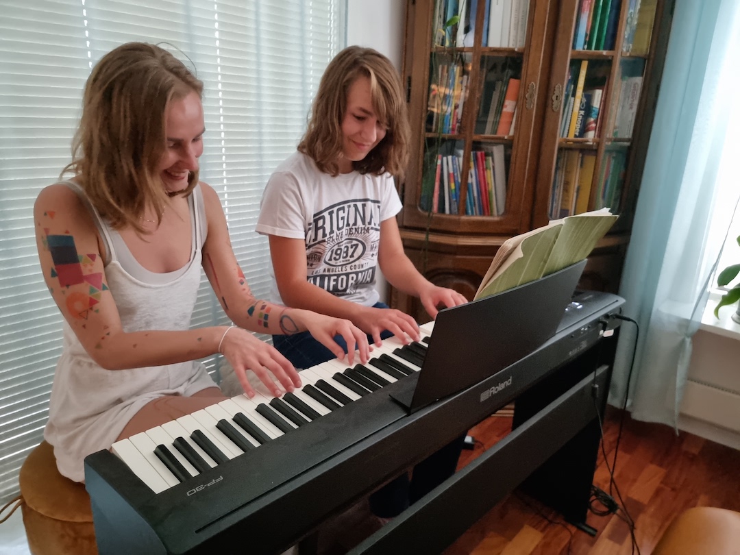 Marta med en ungdomsjente bak et piano