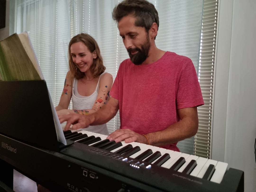 Marta med en voksen mann bak et piano